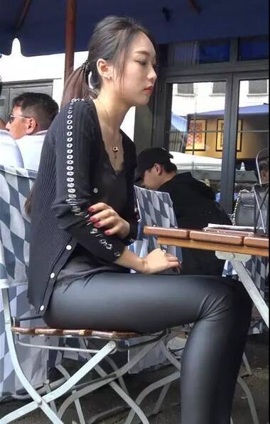 街拍:穿紧身黑皮裤绑马尾辫坐着的性感美女