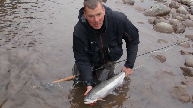 冰天雪地，男子小河边钓鳟鱼，其乐无穷！