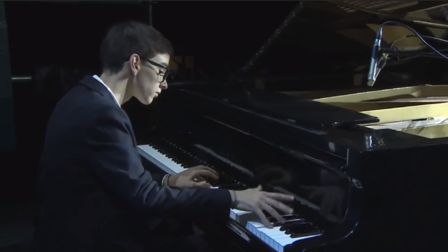钢琴少年一身西装，十指翻飞，弹奏出最美妙的音乐.
