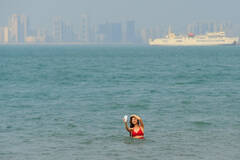 海口一女子持手机站海中自拍 