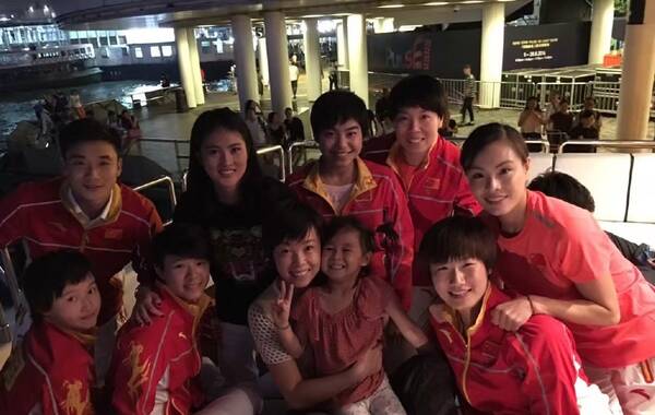 近日，奥运精英代表团在香港访问，乒乓球大满贯得主张怡宁带着女儿与师弟师妹以及跳水队成员相聚，“小魔王”俏俏一改冷漠脸，与乒乓球队成员合影，笑容满面。