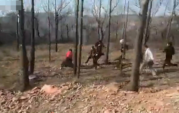 16日网传一段视频显示，在郑州某小树林中，一行十余人围殴暴打一警察，警察后倒地不起。图为打人者暴打警察。（视频截图）