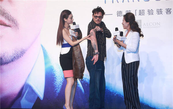 凤凰网娱乐讯 好莱坞著名影星约翰尼-德普日前来到北京，参加4月18日上映的科幻片《超验骇客》的中国宣传活动。在上午颇为混乱的发布会上，德普现场上演“脱衣秀”为大家展示了自己的纹身，晚上，在红色气氛浓郁的北京798园区里，德普与台湾歌手陶喆一起弹吉他翻唱了崔健的名作《一无所有》。图为德普向中国观众秀纹身。