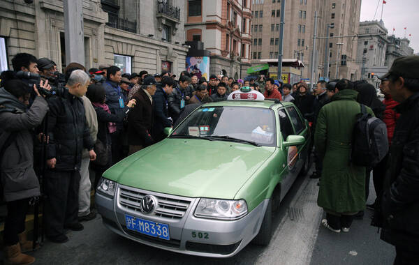 2015年1月6日，上海外滩陈毅广场旁观景平台旁中山东一路。一名女家属一路表达诉求，然后吸引大批媒体的工作人员包围，最后工作人员将其用出租车送走。（独家版权照片 禁止转载）凤凰网 宇飞 摄