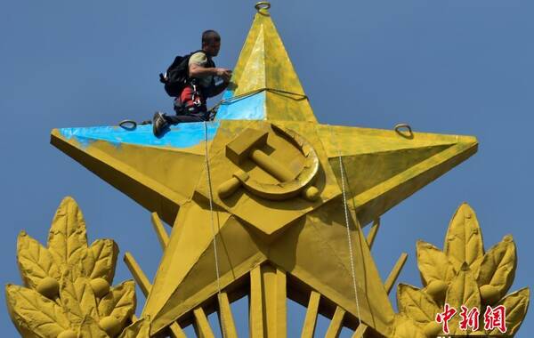 当地时间2014年8月20日，俄罗斯莫斯科，不明身份的男子爬上斯大林式著名建筑“七姐妹”摩天大楼的尖塔，把黄色五角星的一半涂成了蓝色，还插上了一面乌克兰国旗。