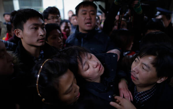 2015年1月1日，上海，在踩踏中受伤者的亲属朋友在第一人民医院等待救治结果。2014年12月31日晚23时35分许，上海市黄浦区外滩陈毅广场发生群众拥挤踩踏事故，致36人死亡，47人受伤。图中为上海交通大学附属第一人民医院，一名踩踏事件中受伤者的亲属因为情绪激动而一度休克。
