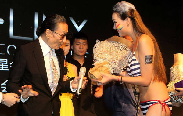 2015年5月28日，79岁的谢贤亮相西安，为儿子谢霆锋在西安投资的酒吧举行的新闻发布会站台。图为谢贤台上获比基尼辣妹献花。