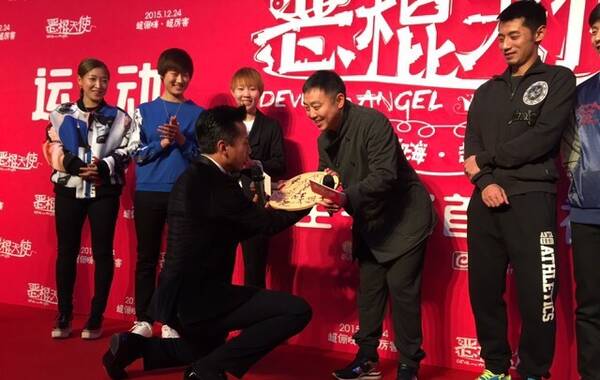 2015年12月21日，邓超在北京举办新片发布会，刘国梁携弟子到场助阵。邓超更是现场“拜师”刘国梁，跪地接受刘国梁赠送球拍。（图片来自电影《恶棍天使》官方微博）