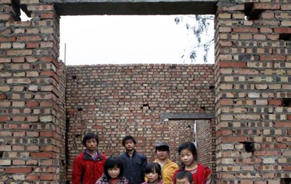 何洪是四川省遂宁市蓬南镇三台村村民，1995年在上海打工时带回一个安徽女人，组建家庭。此后，一个又一个孩子出现在这个家庭。至2012年7月当地政府给何洪妻子安环节育前，两人已生养了11个孩子，被当地人称为“超生游击队”。更令当地人不解的是，何洪并未缴纳“超生罚款”，而且除了最后一个小孩给亲戚抱养外，其他孩子都上了户口。图为何家的9个孩子在他们新建的砖房里合影。