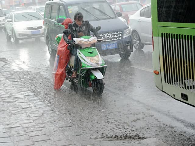 暴雨中爸爸妈妈奋不顾身护着孩子,顺着脸颊流