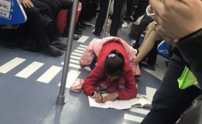 女孩趴地铁上写作业 市民感叹“太不容易”