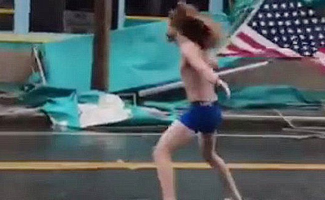 男子在飓风中举国旗赤裸站立