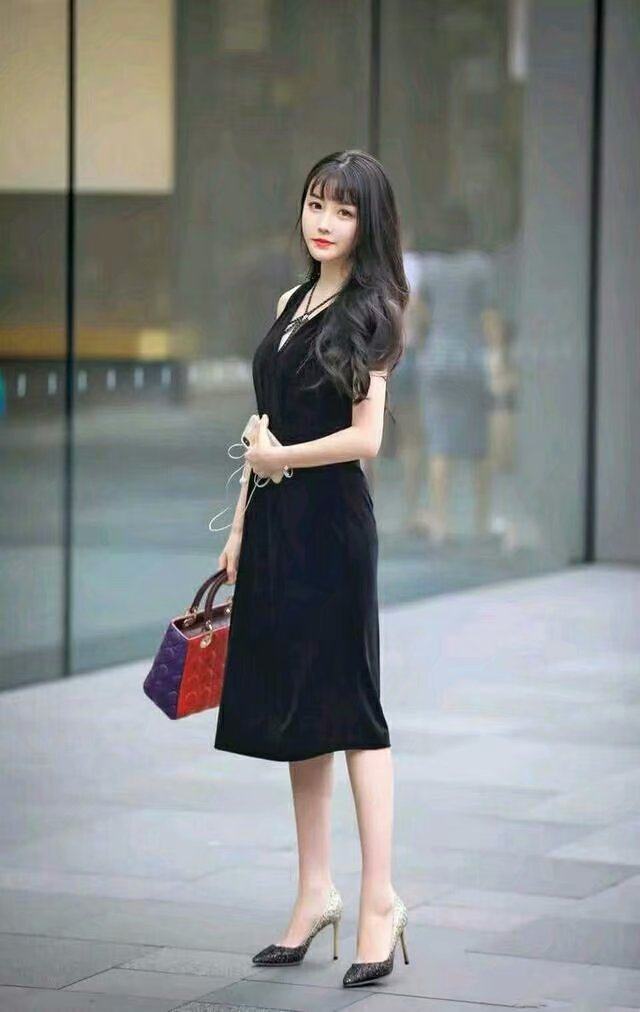 黑色的裙子搭配黑色的高跟鞋,这位美女的头发非常的漂亮,手上拿着一个