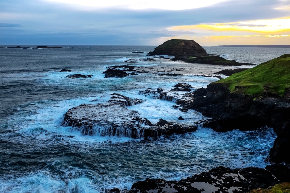 海浪有節奏地拍打著岸邊的嶙峋怪石,明媚陽光下,巨石黑亮亮地令人炫目