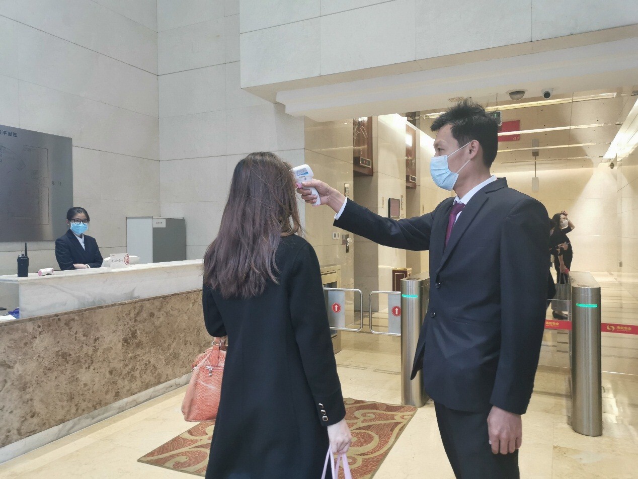 (海航物业某写字楼工作人员对人员测温 海航物业供图)