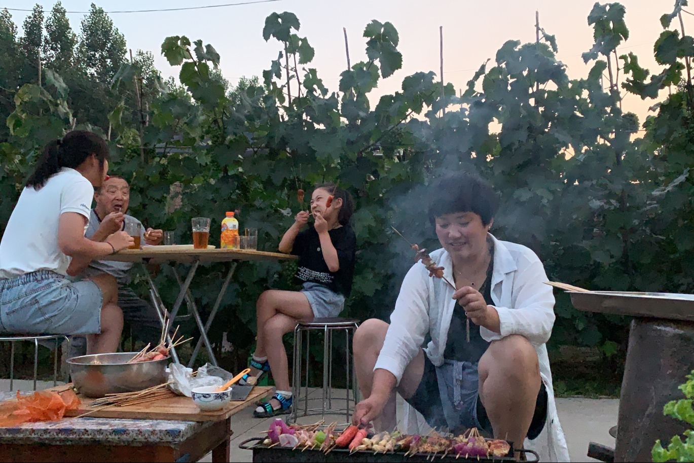 夜幕下的农家院,一家人围坐桌前吃烧烤,大口吃肉大口喝酒,过瘾