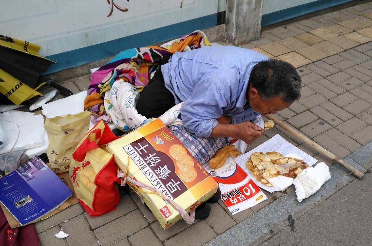 老人錢被偷無奈露宿街頭,趴地喝豆腐腦,希望靠撿破爛掙回家路費