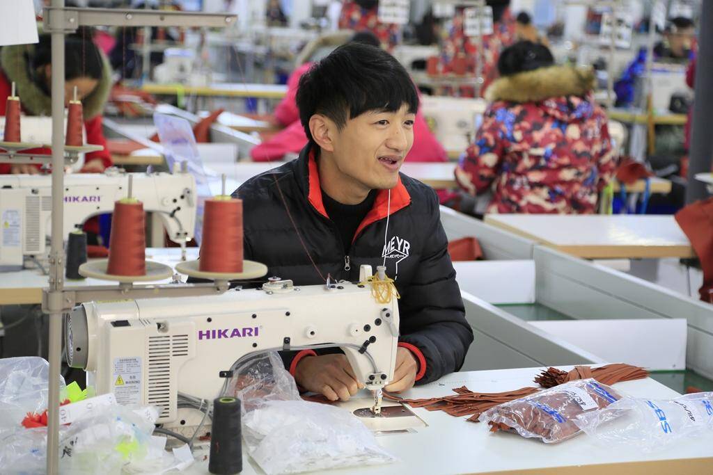 1/8 12月2日,在开发区一家服装厂,一位帅哥正在服装加工车间加工出口