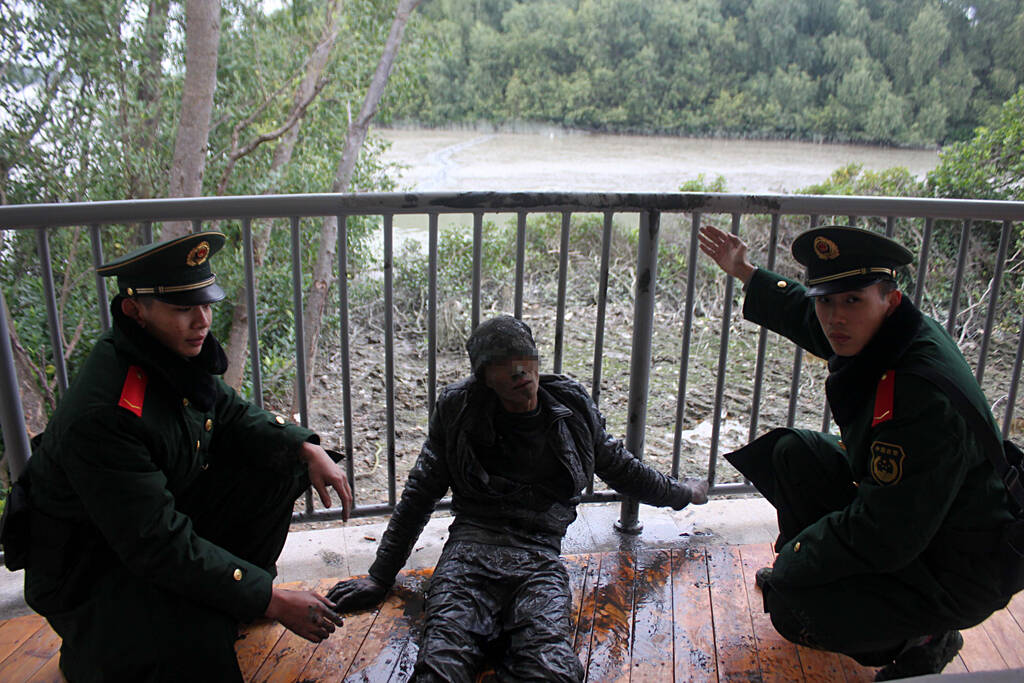 图为从泥水中偷渡上岸的偷渡人员已筋疲力尽.