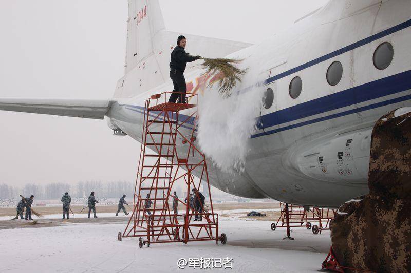 中国空军运-8遭大雪覆盖 地勤用鸡毛掸子除雪