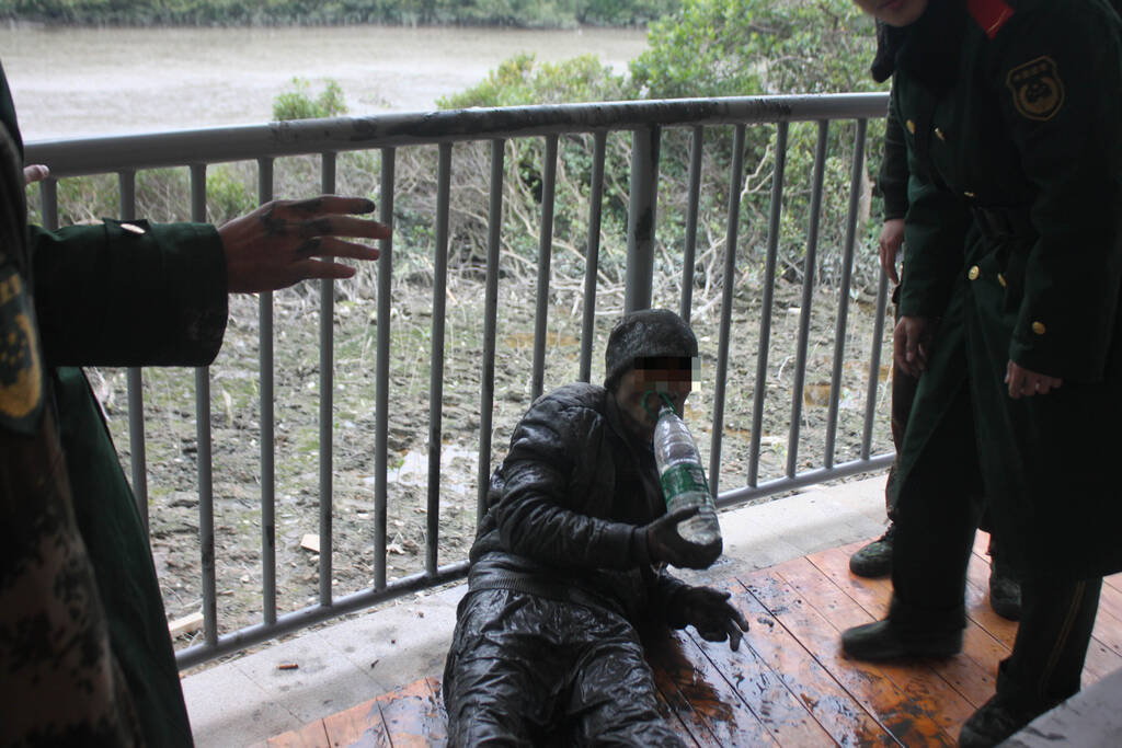 图为从泥水中偷渡上岸的偷渡人员已筋疲力尽.