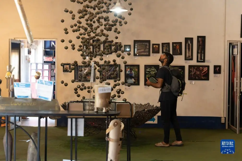 7月11日，一名男子在老挝首都万象“义肢与矫形合作事业”展馆里观看模拟美军散布集束弹药的展品。（图源：新华社）