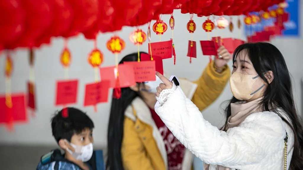 2023年2月3日，江苏泰州站候车厅内，旅客在猜以法治文化为主题的灯谜。视觉中国 图