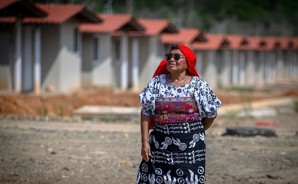 当地时间2023年8月30日，巴拿马卡蒂港，库那族妇女玛格达莱娜·马丁内斯 (Magdalena Martinez)在新社区房子外拍照。