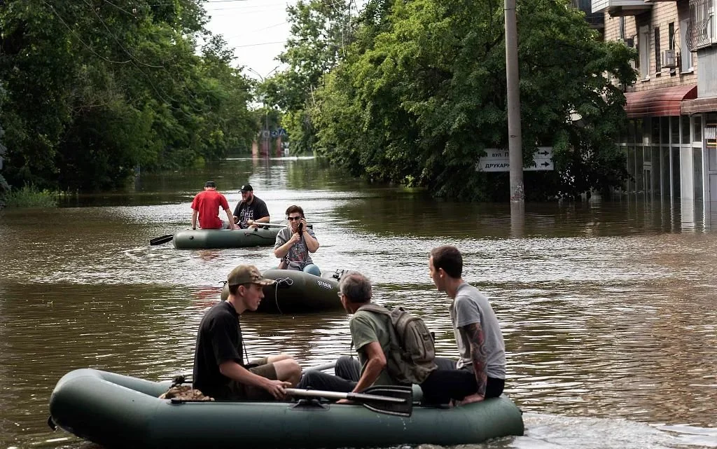 当地时间2023年6月8日，赫尔松地区，卡霍夫卡水电站大坝遭受破坏后，志愿者们在洪水地区用充气船运送当地居民撤离。