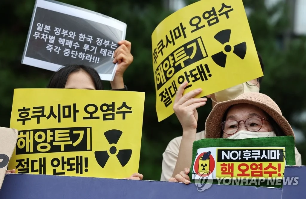8月22日，在首尔钟路区的日本驻韩大使馆前举行的要求日本撤回核污染水排海决定的记者会上，参与人员手举标牌。图源：韩联社