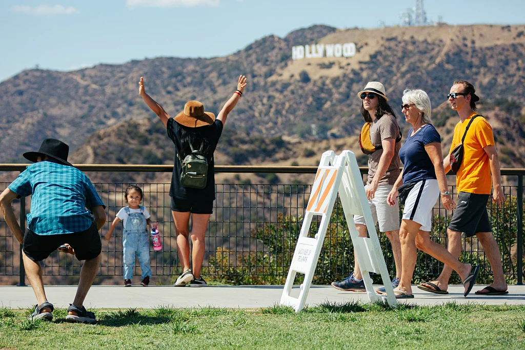 当地时间2022年9月4日，美国洛杉矶，游客们在好莱坞标志前拍照。