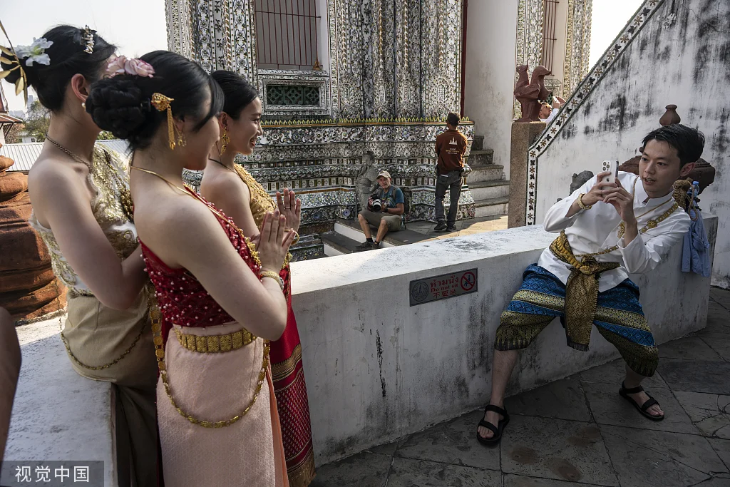 当地时间2024年1月17日，泰国曼谷，中国游客身着泰国传统服饰在郑王庙拍照留念。（图源：视觉中国）