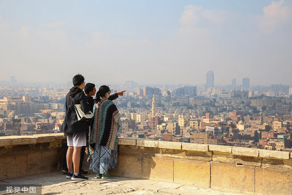 当地时间2023年12月18日，埃及开罗，游客在萨拉丁城堡眺望城市天际线。（图源：视觉中国）