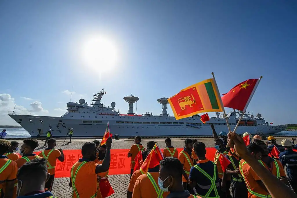 当地时间2022年8月16日，斯里兰卡汉班托塔港，中国科考船“远望5号”抵达当地，工人们挥舞着中国和斯里兰卡国旗。（图源：视觉中国）
