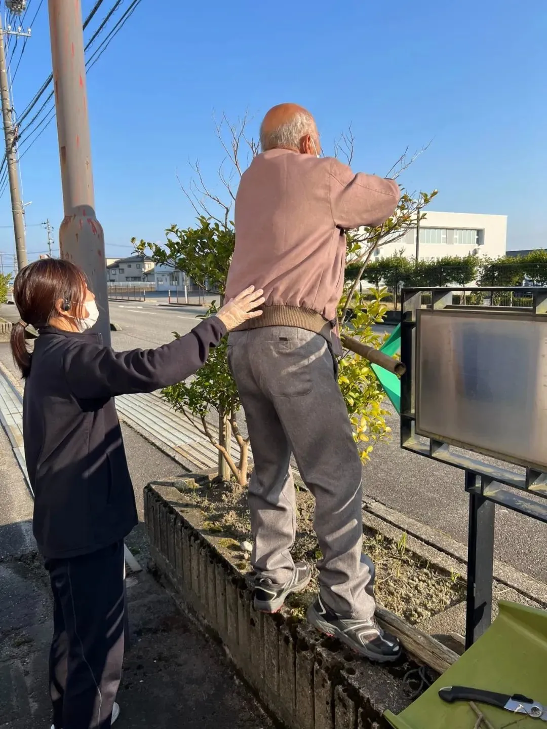 在护理人员的陪伴下,这名老人自行修剪树篱。(图/Facebook@社会福祉法人喜寿会)