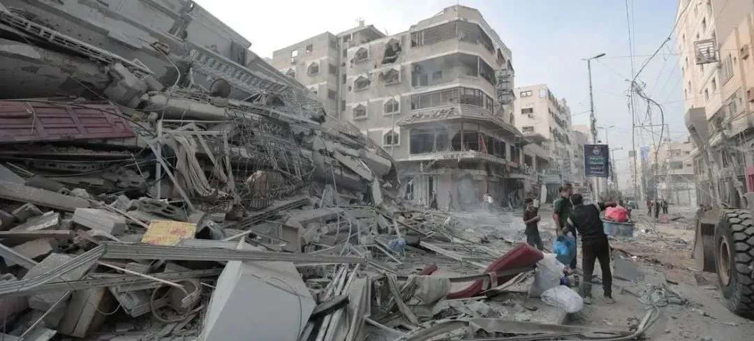 © 近东救济工程处/Mohammed Hinnawi | 轰炸后，加沙的一座建筑物倒塌在街道上。