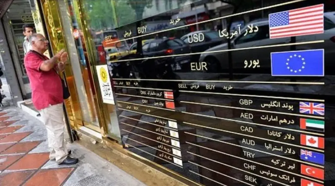▎ 当地人驻足于一家货币兑换所外，旁边是巨大的汇率显示屏，反映了伊朗经济困境下人民对外汇保值的需求日益强烈。图源：iranintl