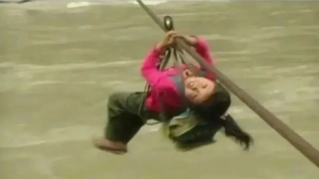 余燕恰幼时坐溜索过江时被媒体拍到的画面。图片来源：视频截图