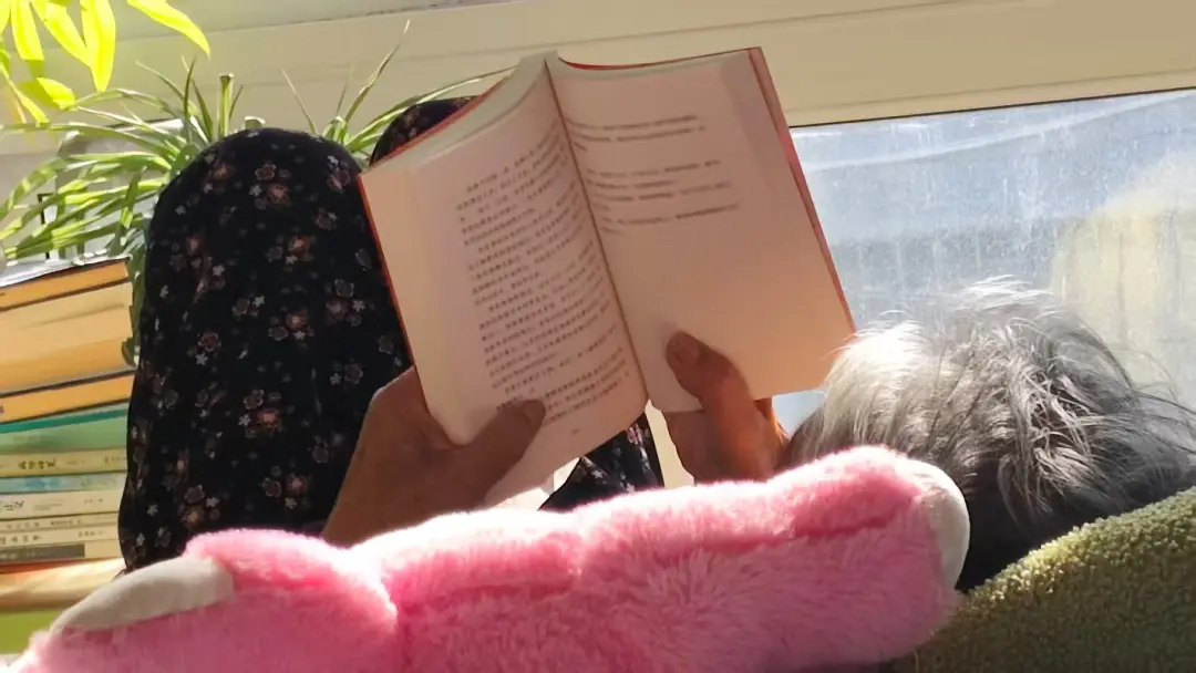 茸茸的姥姥柳树梅在家中翻阅《脐带纪事》实体书。（图/受访者供图）