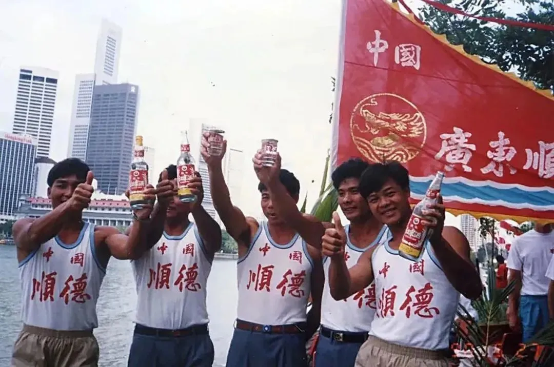 △1983年，顺德龙舟队获胜后，高举酒杯庆祝。（图/红荔红米酒）