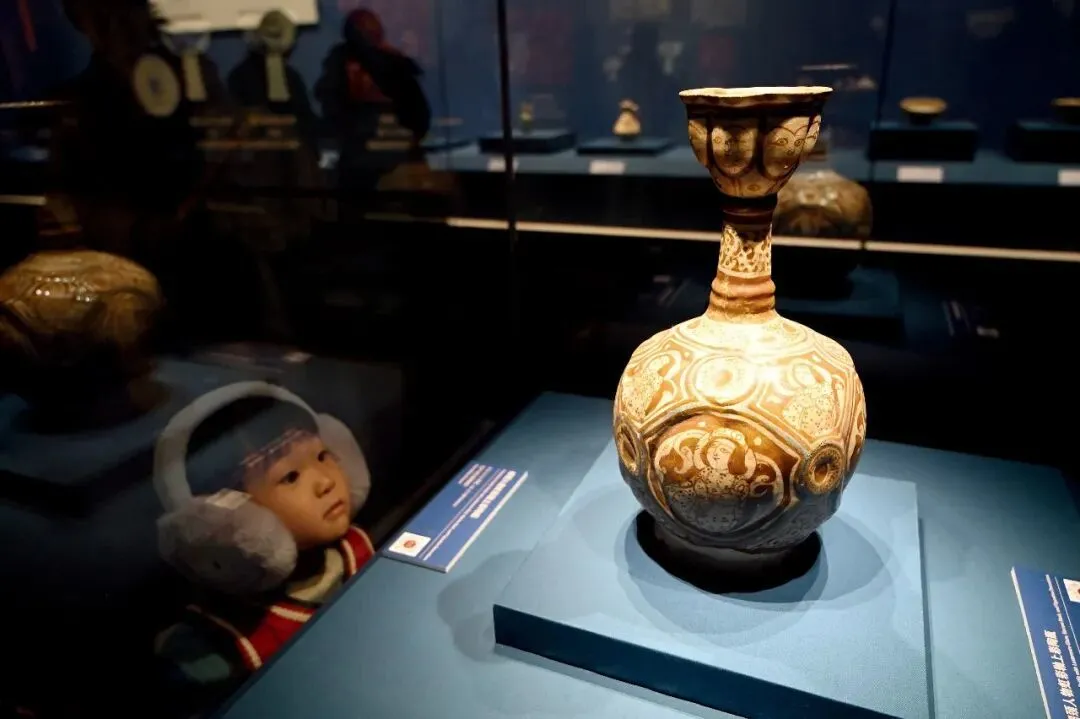 2025年12月20日，“流动的星河——波斯文化艺术瑰宝展”在内蒙古博物院开展。图为公元12—13世纪的“细颈人物虹彩釉上彩陶瓶”。摄影/本刊记者 刘文华