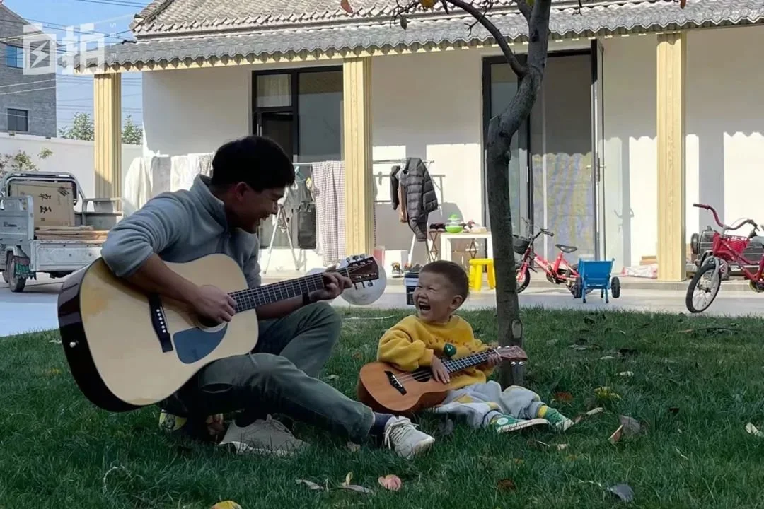 小攀在院子里教鸣仔吉他，鸣仔非常黏他。