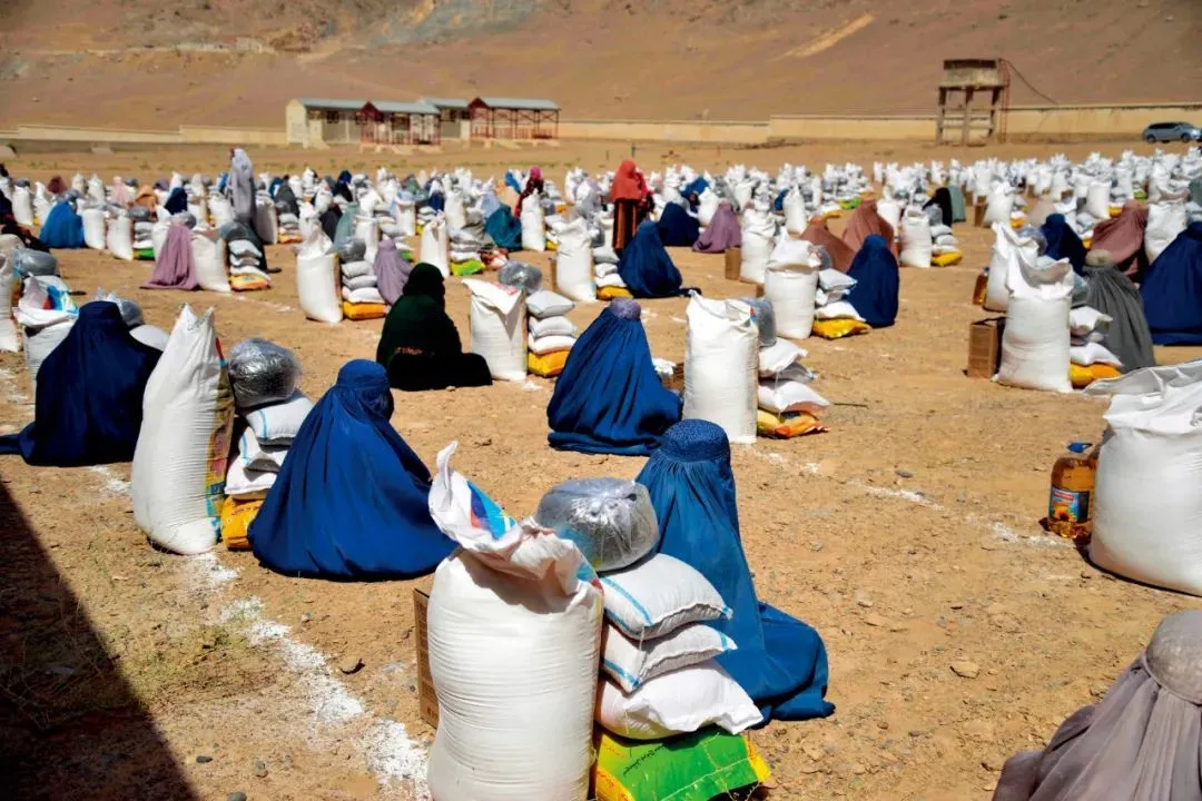 8月10日，阿富汗坎大哈，身穿罩袍的阿富汗妇女等待领取救援食物。图/视觉中国
