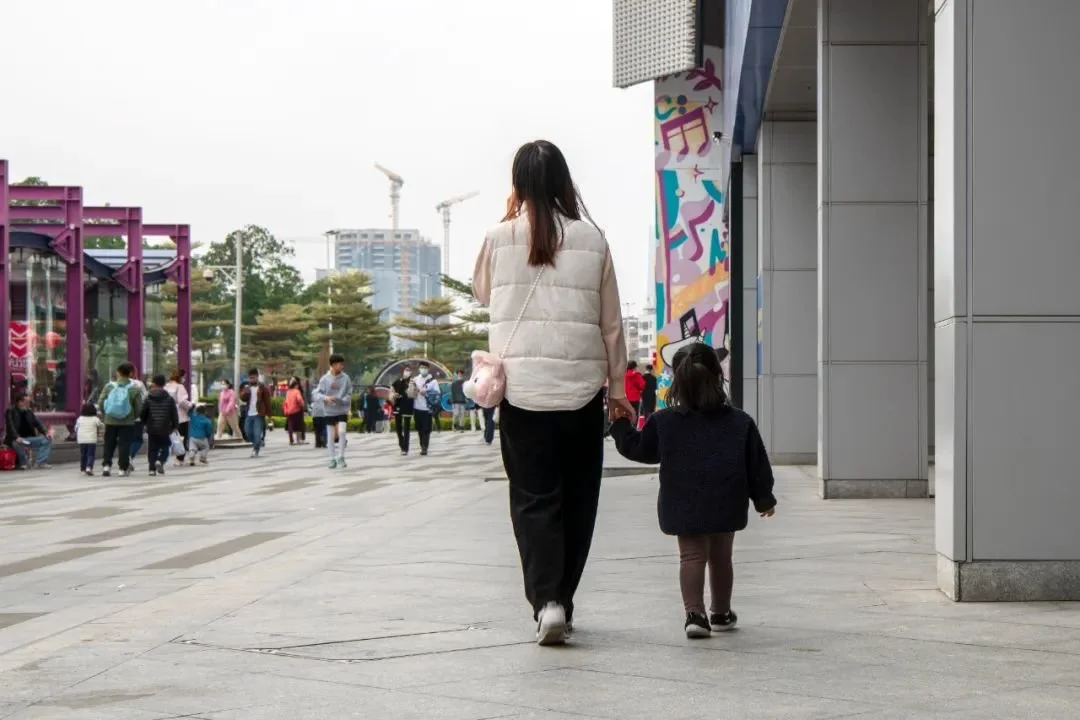 2022年1月9日的广州街头，家长带着孩子经过商场。图源：IC photo