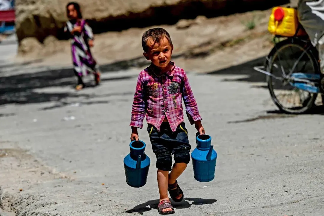 8月3日，阿富汗東北部帕爾旺省，泰蘭馳村一名男孩提著水壺外出取水。本版圖/視覺中國