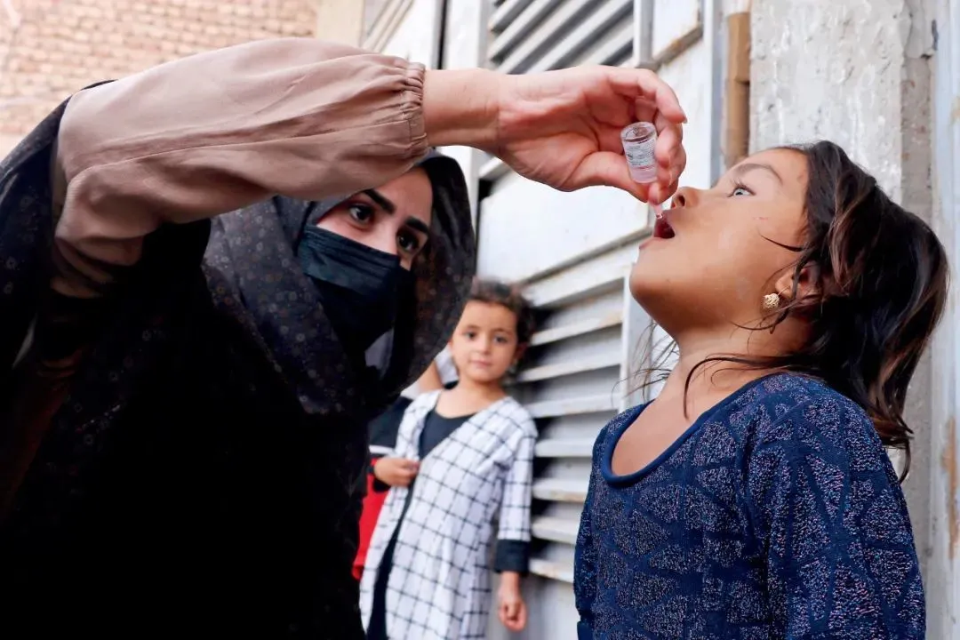 8月21日，阿富汗西部赫拉特省，一名阿富汗女卫生工作者在为儿童注射脊髓灰质炎疫苗。
