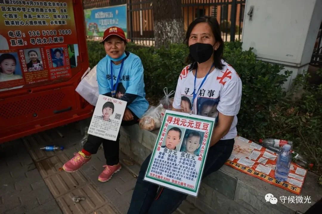 5月1日，山东淄博，张秀红（左）和王妹芝手持寻亲海报坐在街边。中青报·中青网记者 曲俊燕/摄