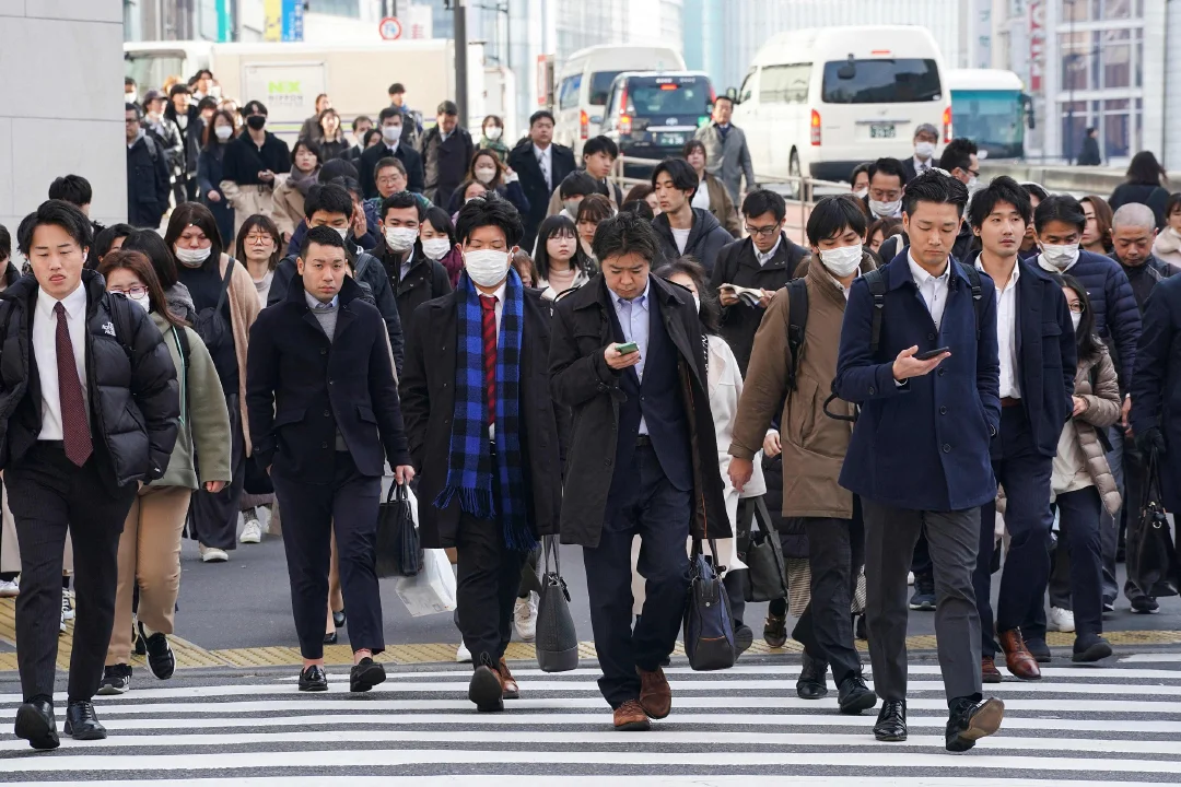 当地时间2024年2月15日，日本东京，早晨通勤上班的人们穿过人行横道。