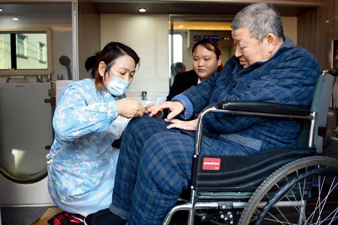 2023年11月19日，浙江慈溪市，助浴师在移动助浴车为一名81岁的老人（右一）修剪指甲。慈溪市在当月启动“长者助浴行动”，让高龄失能半失能老人在家门口就能享受到专业且安全的“助浴”服务。