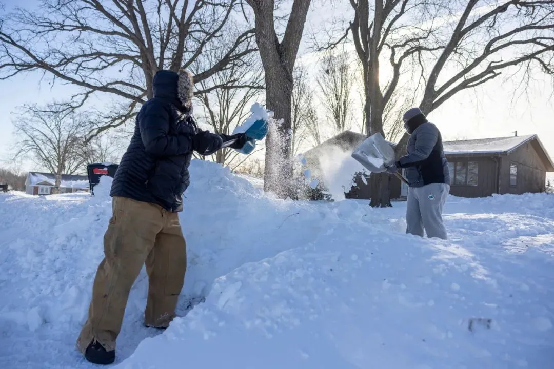 当地时间1月14日，艾奥瓦州党团会议前遇冬季风暴，居民在车道上铲雪。